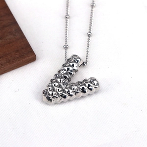 Detailed close-up of a silver V-shaped pendant necklace with textured quilted surface