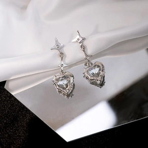 Detail of silver heart earrings with star accents on white silk background