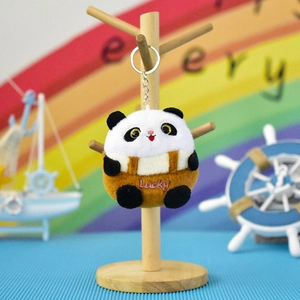 Close-up of a cute panda plush keychain with Lucky embroidery displayed on a wooden stand.