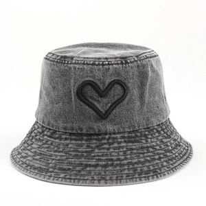 Détail de la broderie cœur et des coutures sur un bob en jean délavé gris foncé