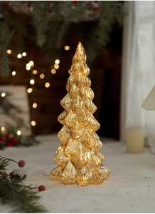 Close-up of golden glass Christmas tree light with warm LED glow on snowy background