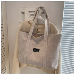 Detailed texture of canvas tote bag with fashion label hanging on a minimalist wall