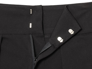 Detailed macro view of high-waisted pleated black trousers with double hook and zipper closure