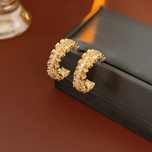 Close-up of 18k gold-plated C-shaped earrings with wave texture and crystal studs