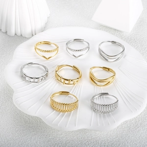Set of 8 gold and silver V-shaped stainless steel rings on a white shell tray