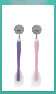 Silicone baking spatulas in pink and purple hanging on hooks for easy storage