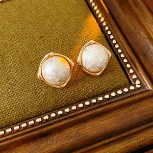 Macro shot of French vintage gold plated earrings with textured white cotton pearls