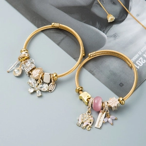Detail of golden charm bracelets with elephant, butterfly pendants and pink beads