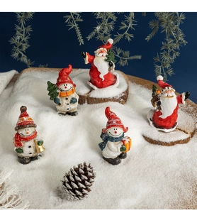 Close-up of five resin Christmas figurines with Santa and snowmen on faux snow base