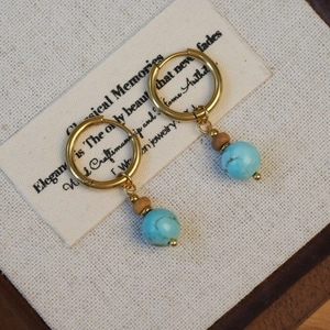 Gros plan de créoles vintage dorées avec perles turquoise sur papier cartonné