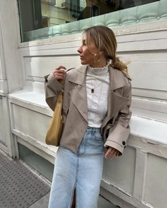 Trincea corta kaki alla moda abbinata a gonna di jeans e borsa a mano gialla