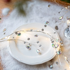 Acrylic aurora crystal Christmas tree branch light on white plate with artificial snow