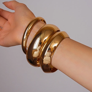 Detail of three-piece set of polished gold geometric bangles styled on female wrist