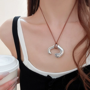 Close-up of irregular silver abstract geometric pendant on brown cord necklace