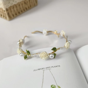 Macro shot of ivory resin roses and pearls on a gold vine headband over a book