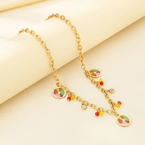Dettaglio della collana dorata con ciondoli a forma di frutta in smalto e strass lucidi