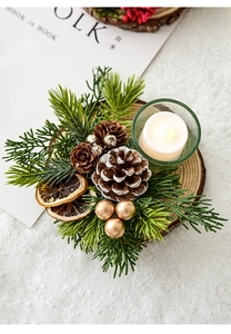 Macro view of Christmas candle holder with wooden base, pine cones, and warm glass tea light