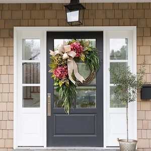 Close-up of farmhouse artificial hydrangea wreath with burlap bow on dark grey door
