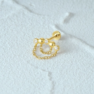 Macro shot of 925 silver gold-plated piercing stud with dangling tassels and crystals