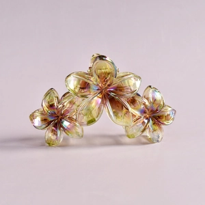 Detail of a transparent iridescent flower-shaped hair claw clip with yellow rainbow shimmer
