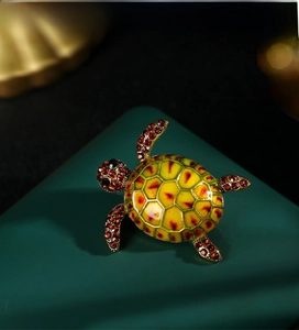 Close-up of golden turtle brooch featuring red enamel shell and sparkling red rhinestones