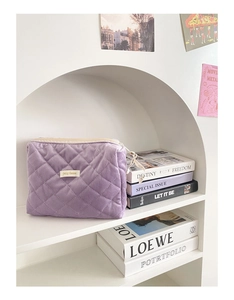Détail d'une trousse à maquillage violette en velours côtelé matelassé sur étagère