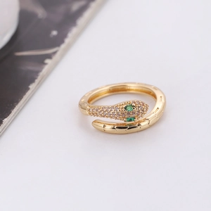 Detail of gold snake ring featuring green gemstone eyes and pavé crystal head