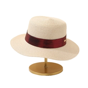 Minimalist beige flat top straw hat with deep red ribbon and gold logo for summer sun protection
