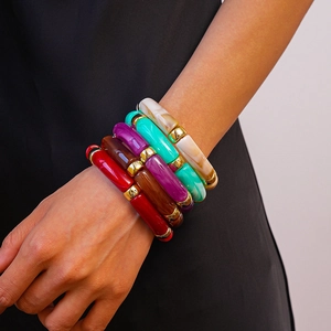 Gros plan de bracelets en résine colorée style bambou avec séparateurs dorés au poignet