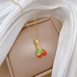 Détail du collier cerise doré avec émail rouge et feuilles vertes sur de la soie