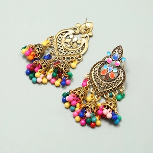 Detailed shot of antique gold Jhumka earrings with colorful beads on a grey backdrop