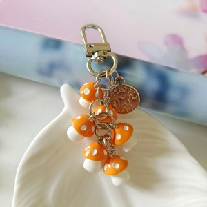 Detail of cute orange polka dot mushroom charms with silver lobster clasp and logo tag