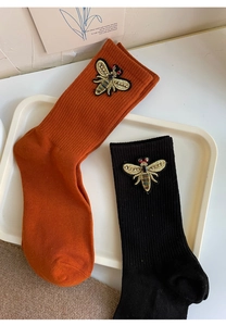 Detailed view of ribbed mid-calf socks with 3D bee embroidery in orange and black