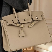 Detailed macro view of beige pebble grain leather texture and metal lock on luxury handbag