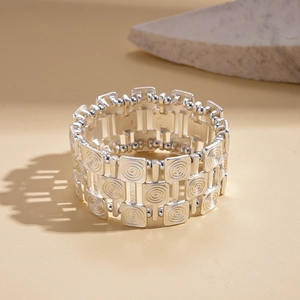 Macro detail of silver twisted metal bracelet with square links and relief texture