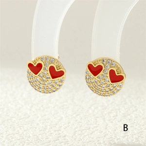 Detailed macro view of gold plated stud earring with zircon inlay and red enamel hearts