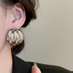 Detailed close-up of a silver multi-layer spiral textured earring worn by a model