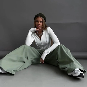 Dettaglio dei pantaloni cargo a gamba larga verde salvia con top in maglia bianca