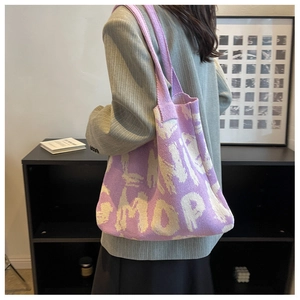 Detail view of purple and beige knitted tote bag worn on shoulder by a model