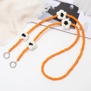 Crossbody phone chain with orange velvet beads and black white knit flower charms
