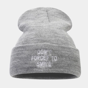 Detailed view of grey knit beanie with white Don't Forget To Smile embroidery