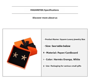 Detail of luxury orange jewelry gift box with black ribbon and floral stud earrings