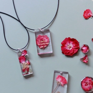 Collana in resina fatta a mano con vere rose rosse essiccate e testo in foglia d'oro su grigio