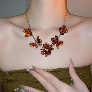 Close-up of leopard petal necklace with amber pendants and gold chain on model