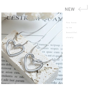 Detail of silver heart pendants on elegant snake chains over textured white stone