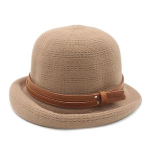 Close-up of camel knit bucket hat featuring brown leather band with metal rivets