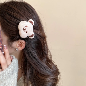 Detail of cream plush bear hair clip with brown embroidery on model side profile