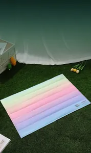 Detalle de alfombra refrescante arcoíris para mascotas sobre césped con logo Kimpets