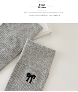 Close-up of gray cotton knee high socks featuring an embroidered black bow detail
