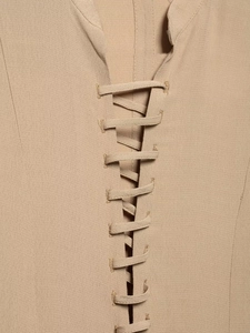 Detail shot of beige chiffon dress showing the intricate lace-up tie and woven texture